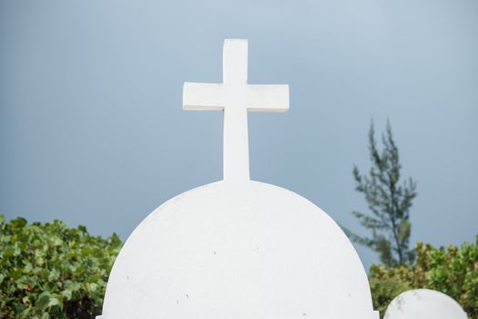 White concrete cross on grave headstone.