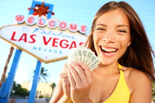 Las Vegas Girl Excited holding money. Winner cheerful in front of Welcome to Fabulous Las Vegas sign. Beautiful young mixed race Caucasian / Chinese Asian female model smiling happy holding gambling money.