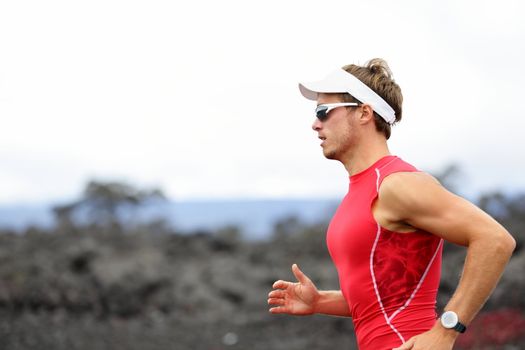 Running triathlon athlete man. Runner triathlete training for ironman on Hawaii. Young Male athlete running in red compression top on volcano in Kailua-Kona, Big Island, Hawaii.