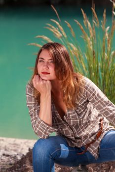 Young woman sitting on an old jerry cans at the lake