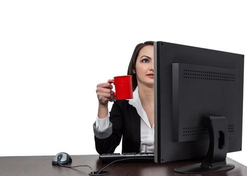 Image of a young businesswoman with a big red cup of coffee in front of her computer at the workplace in the office, isolated against a white background.