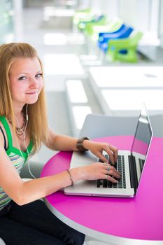 pretty female college student working on her laptop computer on campus, before class (color toned image; shallow DOF)