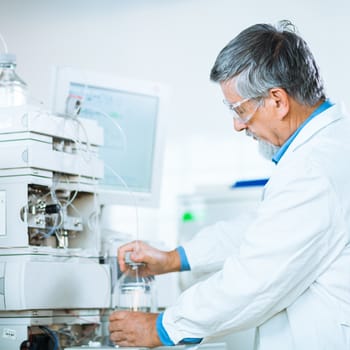 Senior male researcher carrying out scientific research in a lab (shallow DOF; color toned image)