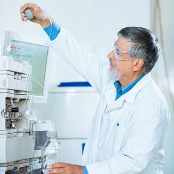 Senior male researcher carrying out scientific research in a lab (shallow DOF; color toned image)