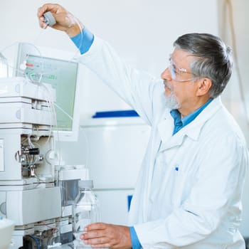 Senior male researcher carrying out scientific research in a lab (shallow DOF; color toned image)