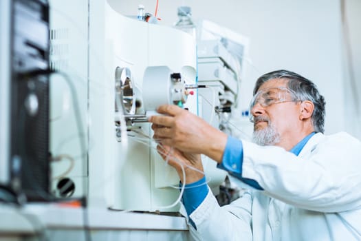 Senior male researcher carrying out scientific research in a lab (shallow DOF; color toned image)