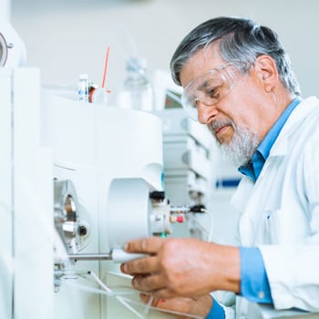 Senior male researcher carrying out scientific research in a lab (shallow DOF; color toned image)