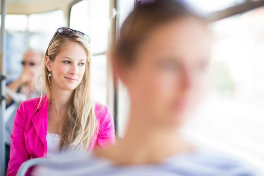 Pretty, young woman on a streetcar/tramway, during her commute to work (color toned image; shallow DOF)