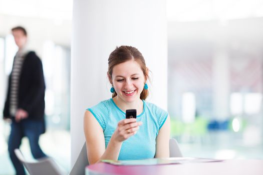 Pretty young woman using her mobile phone/speaking on the phone in a public area (shallow DOF; color toned image)