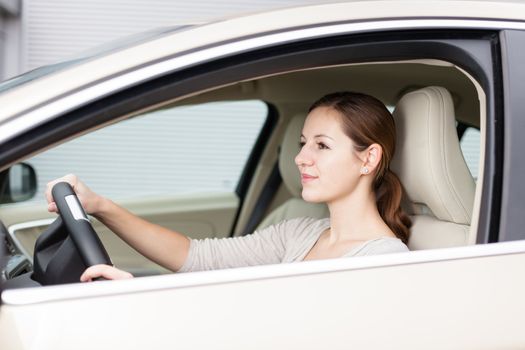 Pretty young woman driving her new car