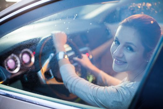 Pretty young woman driving her brand new car shallow DOF; color toned image)