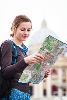 Pretty young female tourist studying a map at St. Peter's square in the Vatican City in Rome