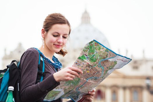 Pretty young female tourist studying a map at St. Peter's square in the Vatican City in Rome