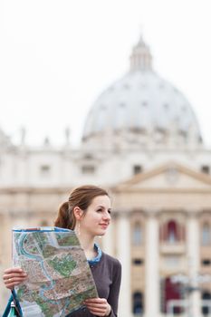 Pretty young female tourist studying a map at St. Peter's square in the Vatican City in Rome