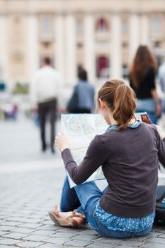 Pretty young female tourist studying a map at St. Peter's square in the Vatican City in Rome