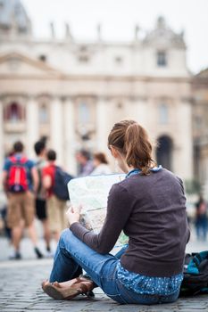 Pretty young female tourist studying a map at St. Peter's square in the Vatican City in Rome