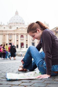 Pretty young female tourist studying a map at St. Peter's square in the Vatican City in Rome