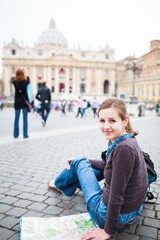 Pretty young female tourist studying a map at St. Peter's square in the Vatican City in Rome