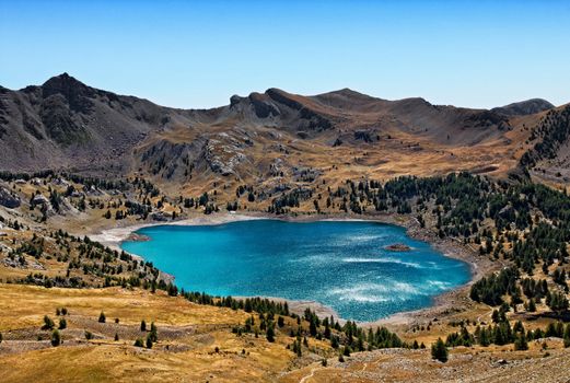 Image of Lac D'Allos (2228 m) during a windy day with sunlight relections on the rippled water surface. This lake  is the largest natural lake (54 ha)  in Europe at this altitude.It is located in The South Alps (Alpes de Haute Provence) in The Mercantour National Park in South-East of France.