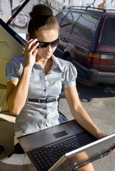 businesswoman has a fan with laptop in black car