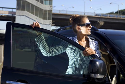 happy business woman in sunglasses near the car against city bridge