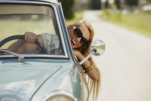 Smiling woman driving vintage car.