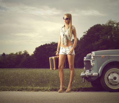 Young sexy girl with suitcase and vintage cars