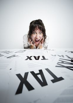 Astonished woman looking at a bunch of worrying tax forms on her desk