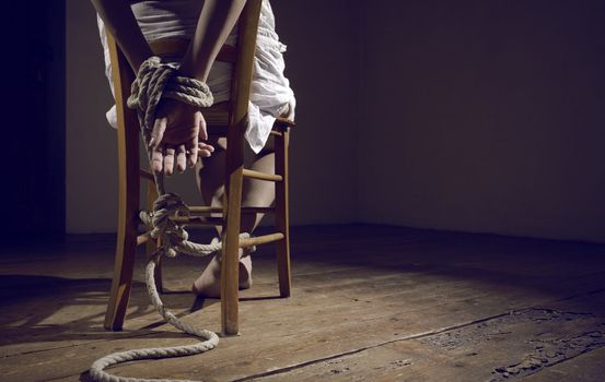 Young woman tied to a chair in a empty room