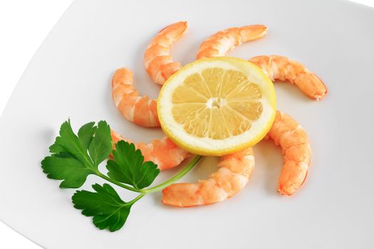 closeup of shelled shrimps with lemon and parsley on a white plate