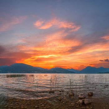 Colorful sunrise on Lake with majestic clouds, Alpes mountains on background