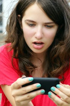 Young woman, teenager girl or student shocked at what she is reading on her cell phone, perfect for online intimidation or bullying at school.