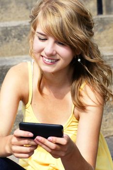 Young woman, teenager girl or student writing text,texting,on her cell phone or mobile and smiling, perfect for social media, networking or other internet technology.