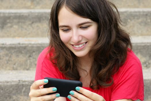 Young woman, teenager girl or student reading text on her cell phone and smiling, perfect for social media, networking or other internet technology.