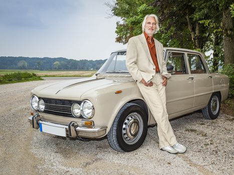 An image of a handsome man in front of his historic car