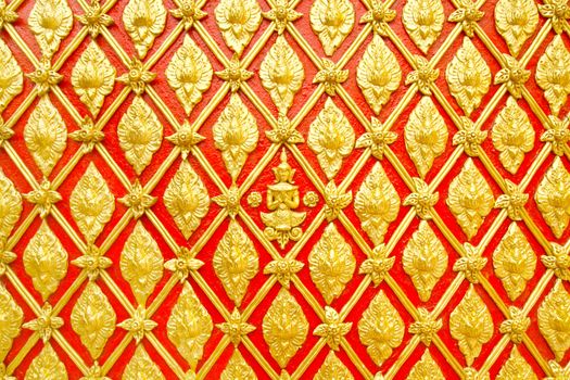 Stucco Thai pattern on wall are decorated with gold color on red background.