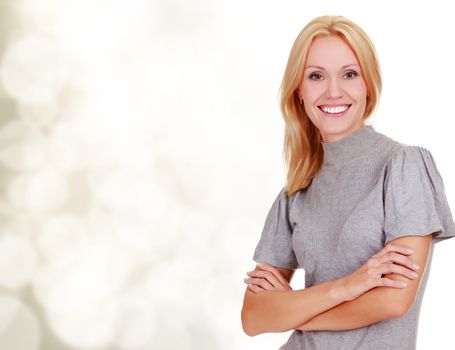 Smiling woman standing with arms folded against a blurred background