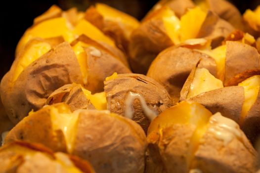 Riven baked patatoes in the oven with yellow cheese 