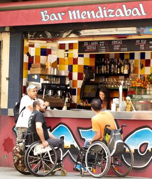 BARCELONA - MAY 26: The people in invalid prams are communicating with a waitress at the counter of a street bar on May 26, 2012 in Barcelona, Spain.