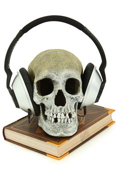 Audiobook concept with human skeleton wearing audio headset sitting on book.