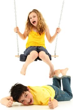 Adorable child couple portrait, girl kicks boy on ground while swinging.  Over white background.