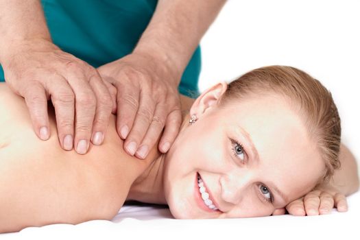 A young pretty girl of 25 on a seance of medical (health) massage in a light study. She’s smiling and looking at the camera.