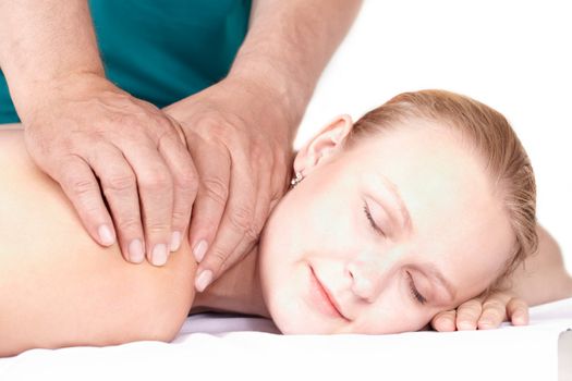 A young pretty girl of 25 on a seance of medical (health) massage in a light study. Her eyes are closed, a light smile on her face.