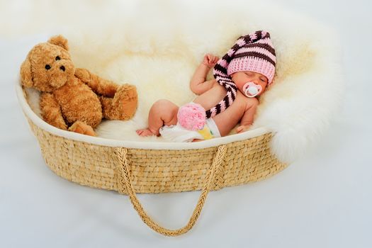 infant sleeping on a white sheepskin in a wicker basket.