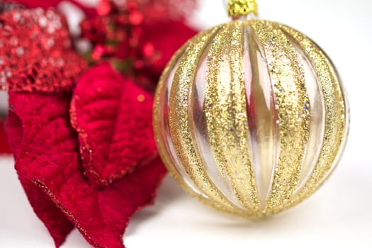 A vibrant red poinsettia with a gold decorated glass bauble