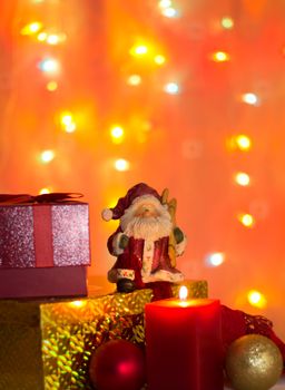 Santa Claus with christmas gifts illuminated by a candle