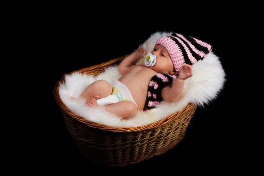 Newborn Child in a wicker basket on a black background.