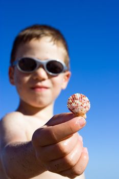 A young child on the beach showing shell