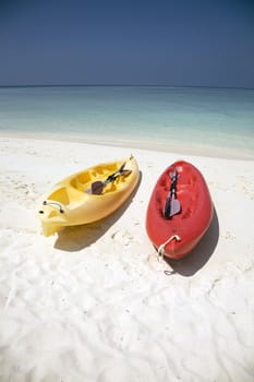 Red and yellow canoes resting on a sandy beach.