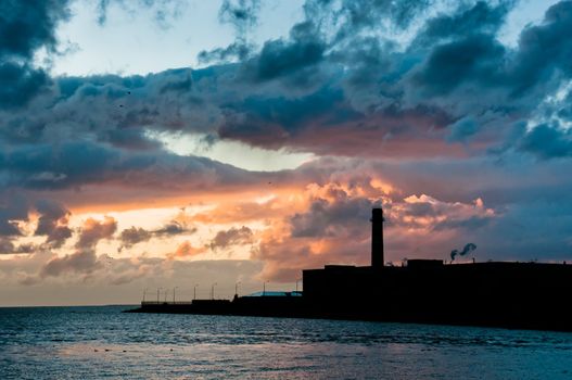 Factory silhouette with beautiful cloudscape on background at sunset time